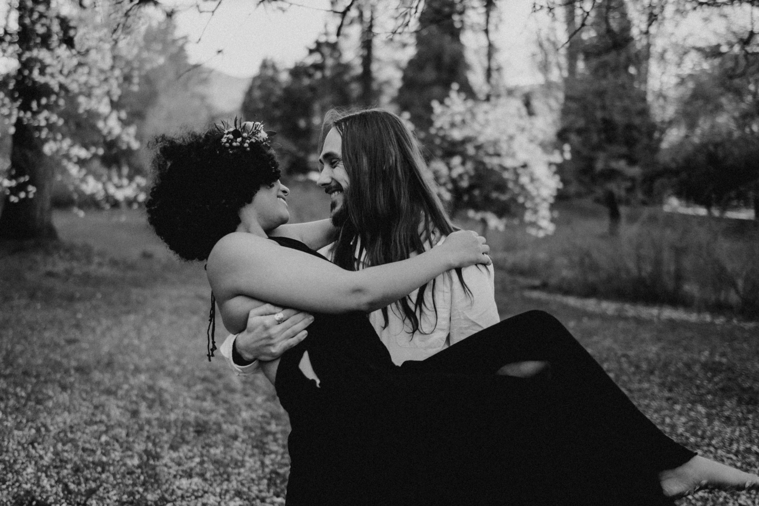 Black and white image of a man holding his girlfriend in both arms in wedding style